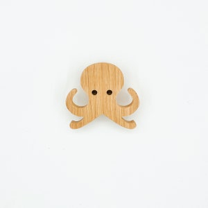 Peut inclure: Un crochet mural en bois en forme de pieuvre avec une finition en bois naturel. Le crochet a huit tentacules et deux trous pour accrocher des objets.