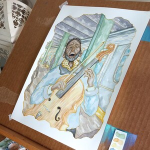 K&ouml;nnte beinhalten: Aquarellgem&auml;lde eines Mannes, der in einer U-Bahn-Station Cello spielt. Der Mann tr&auml;gt eine blaue Jacke und hat einen Bart. Das Cello ist braun und hat eine goldene Saite. Der Hintergrund ist ein Aquarell aus Blau und Gr&uuml;n.