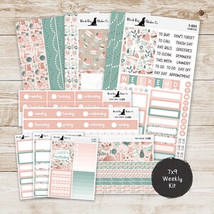May include: A 7x9 weekly kit with stickers featuring a floral and cupcake design in shades of pink, teal, and beige. Includes labels for the days of the week, to-do lists, and decorative elements. The text "Happy Birthday" and "Cheers!" are visible.
