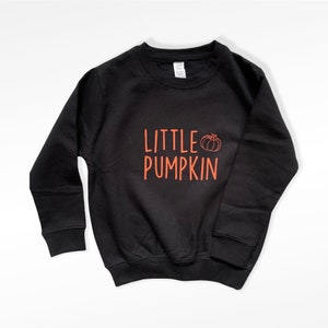Könnte beinhalten: Schwarzer Pullover mit dem Text "LITTLE PUMPKIN" in Orange und einer kleinen Kürbisgrafik.
