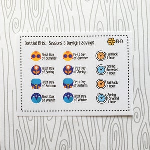 May include: A sheet of stickers with illustrations of the four seasons and clocks indicating the first day of each season and the time change for daylight savings. The text reads "Bottled Bits: Seasons & Daylight Savings" and "BHD".