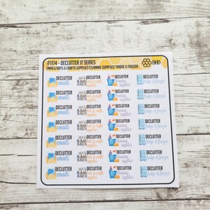 May include: A sheet of planner stickers with the text "DECLUTTER" and various categories like "emails," "arts & crafts supplies," and "cleaning supplies." The stickers are in a grid layout with a white background and black borders.