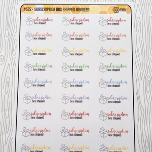 May include: A sheet of colorful stickers with the text "subscription box shipped" in various colors and fonts. The stickers are designed to be used for labeling packages or marking items as shipped.