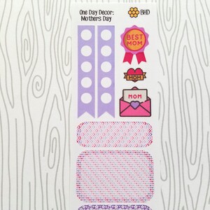 May include: A sheet of decorative stickers with a Mother's Day theme. The stickers include a "Best Mom" ribbon, heart-shaped accents, and an envelope with "Mom" on it. The color palette is primarily purple, pink, and red.