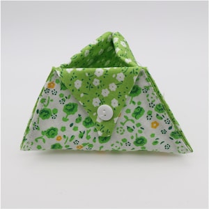 May include: A triangular fabric pouch with a white button closure. The pouch is made of green and white floral patterned fabric. The interior is a solid green fabric with white floral accents. The pouch is designed to fold closed.