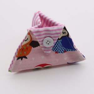 May include: A pink triangular fabric pouch with a white button closure. The pouch is decorated with a colorful owl print and pink and white stripes.