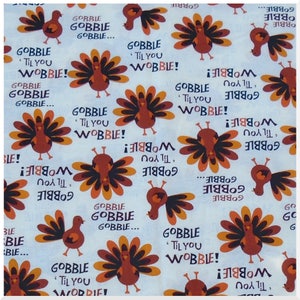 May include: A white fabric with a repeating pattern of turkeys with orange, brown, and black feathers. The turkeys are surrounded by the text "Gobble 'Til You Wobble!" in various colors and sizes.