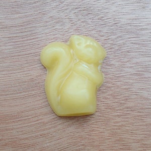 May include: A yellow beeswax candle shaped like a squirrel.
