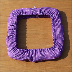 May include: Purple fabric hoop with white heart pattern, designed for embroidery projects.