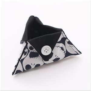 May include: A small triangular fabric pouch with a black and white skull print. The pouch has a black lining and a white button closure.