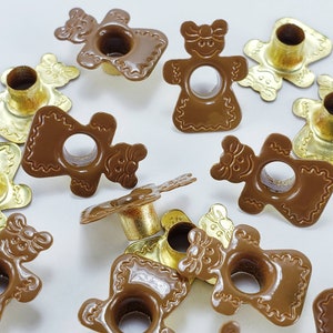 May include: Assortment of brown and gold metal candle holders shaped like bears. The candle holders have a hole in the center for a candle.