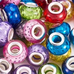 Può includere: Una collezione di perline di vetro colorate in varie tonalità di blu, viola, rosa, rosso e verde. Ogni perlina ha un'anima in metallo color argento. Le perline sono rotonde e hanno un foro al centro, adatte per la creazione di gioielli.