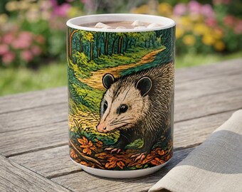 May include: A ceramic mug featuring a detailed illustration of an opossum walking along a forest path. The design includes vibrant green trees, a winding dirt trail, and fallen orange leaves. The mug is filled with a hot beverage topped with marshmallows.