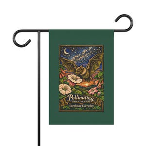 Puede incluir: Una bandera de jardín verde con una ilustración de un murciélago, flores y un cielo estrellado. El texto en la bandera dice "Pollinating Under the Stars Earthday Everyday."