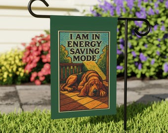 Peut inclure: Un drapeau de jardin vert avec le texte "I AM IN ENERGY SAVING MODE" et une illustration d'un chien de chasse endormi. Le drapeau est affiché sur un support en métal noir dans un jardin. Le chien est allongé sur une terrasse en bois.