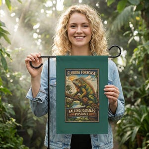 May include: A green garden flag with the text "FLORIDA FORECAST: FALLING IGUANAS POSSIBLE" and a colorful illustration of an iguana on a tree branch. The flag is held up by a black metal stand, perfect for outdoor decor.