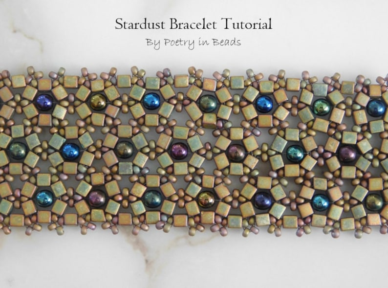 Pu&ograve; includere: Un primo piano di un braccialetto di perline con un motivo geometrico. Il braccialetto &egrave; realizzato con piccole perline quadrate in tonalit&agrave; dorate, verdi e marroni. Le perline sono intervallate da perline rotonde iridescenti in tonalit&agrave; blu, verdi e viola. Il braccialetto &egrave; chiamato "Stardust Bracelet Tutorial" di "Poetry in Beads".
