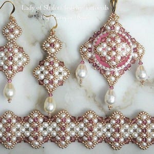 Op de afbeelding: Een set roze en witte parelsieraden, inclusief een ketting met hanger, oorbellen en een armband. De sieraden hebben een delicaat ontwerp met kleine parels en kristallen.