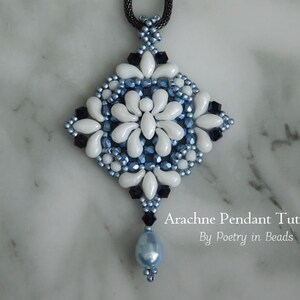 K&ouml;nnte beinhalten: Ein wei&szlig;er und blauer Perlenanh&auml;nger mit einem schwarzen Perlen-Tropfen, der ein geometrisches Design aufweist. Der Anh&auml;nger befindet sich auf einer wei&szlig;en Marmorfl&auml;che. Arachne Pendant Tutorial by Poetry in Beads.