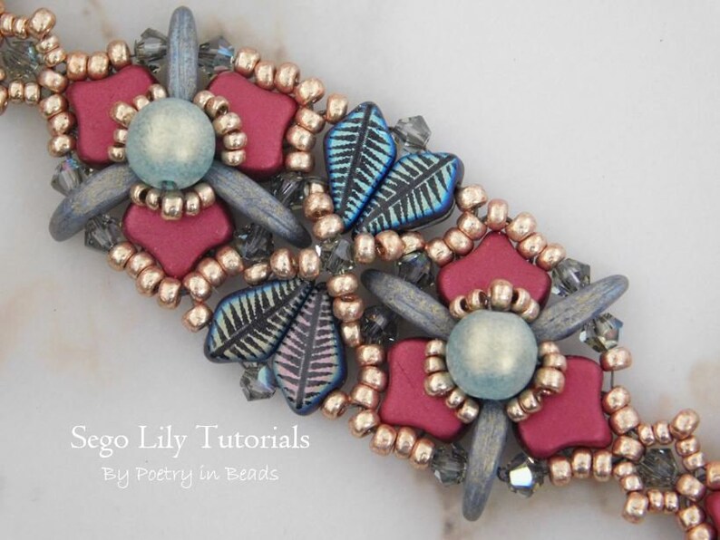 May include: A close-up of a beaded bracelet with a floral design. The bracelet features red, blue, and gold beads, as well as small silver beads. The bracelet is made with a variety of different bead shapes and sizes. The text "Sego Lily Tutorials By Poetry in Beads" is visible in the lower left corner of the image.