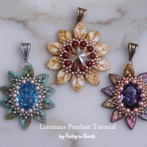 May include: Three handmade Luminara pendant necklaces in a floral design. The pendants feature a central gemstone surrounded by beaded petals. Colors include blue, cream, and purple. The text "Luminara Pendant Tutorial by Poetry in Beads" is visible.