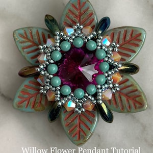 May include: A teal and orange flower pendant with a pink crystal center. The pendant is made with beads and has a detailed design. The pendant is titled "Willow Flower Pendant Tutorial by Poetry in Beads".