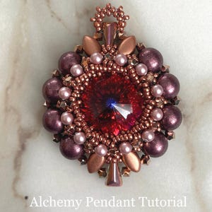 Pode incluir: Um close-up de um pingente de contas vermelhas e cobre com um grande cristal vermelho no centro. O pingente &eacute; cercado por contas menores em tons de rosa e roxo. O pingente est&aacute; pendurado em um la&ccedil;o de fio de cobre.