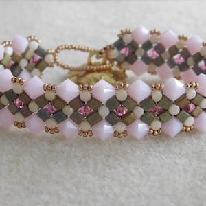 May include: A pink and white beaded bracelet with a gold clasp. The bracelet is made with small, faceted beads in a geometric pattern.