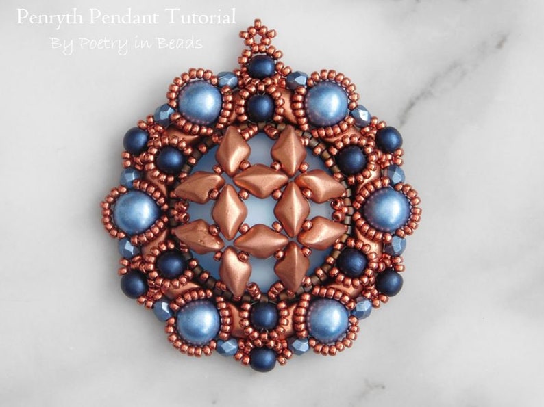 Puede incluir: Un colgante de cuentas de cobre y azul con un dise&ntilde;o de estrella. El colgante est&aacute; hecho con cuentas de semillas y cuentas redondas m&aacute;s grandes.