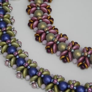 Könnte beinhalten: Zwei Perlenketten mit Blumenmuster. Eine Kette ist aus grünen, blauen und rosa Perlen gefertigt, während die andere aus grünen, rosa und goldenen Perlen besteht.