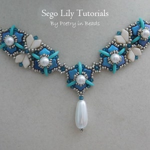 May include: A silver chain necklace with a pendant featuring a cluster of blue and white beads in a flower shape. The pendant is attached to a larger cluster of beads in the same design. The necklace is labeled "Sego Lily Tutorials By Poetry in Beads".