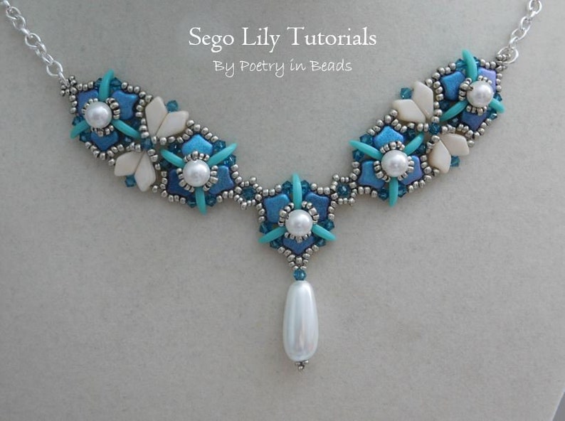 May include: A silver chain necklace with a pendant featuring a cluster of blue and white beads in a flower shape. The pendant is attached to a larger cluster of beads in the same design. The necklace is labeled "Sego Lily Tutorials By Poetry in Beads".