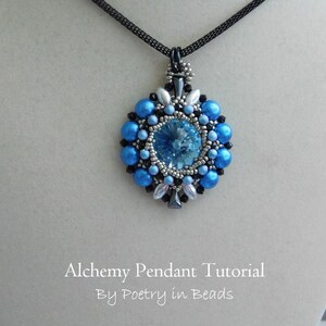 Pode incluir: Um pingente de contas azuis e prateadas com um centro de cristal, pendurado em um cord&atilde;o preto. O pingente est&aacute; etiquetado como "Alchemy Pendant Tutorial by Poetry in Beads".