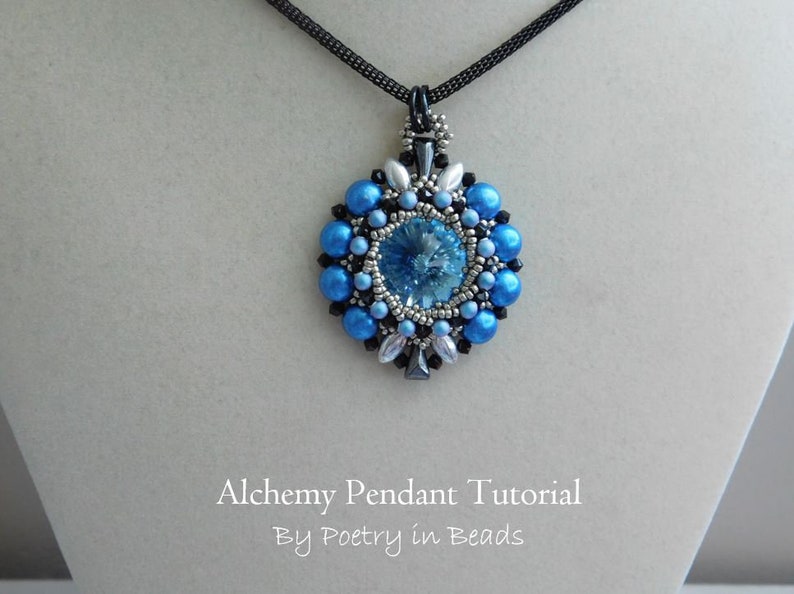 Pode incluir: Um pingente de contas azuis e prateadas com um centro de cristal, pendurado em um cord&atilde;o preto. O pingente est&aacute; etiquetado como "Alchemy Pendant Tutorial by Poetry in Beads".