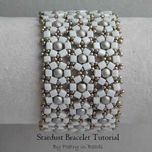 Pu&ograve; includere: Un braccialetto di perline bianche e argentate con un motivo a stella. Il braccialetto &egrave; su una superficie bianca e il testo "Stardust Bracelet Tutorial By Poetry in Beads" &egrave; sotto il braccialetto.