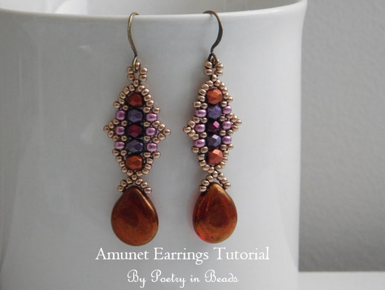May include: A pair of long, beaded earrings with a teardrop-shaped pendant. The earrings are made with small, colorful beads in shades of pink, purple, red, and brown. The teardrop pendants are a shiny copper color. The earrings are displayed against a white background. Amunet Earrings Tutorial by Poetry in Beads.