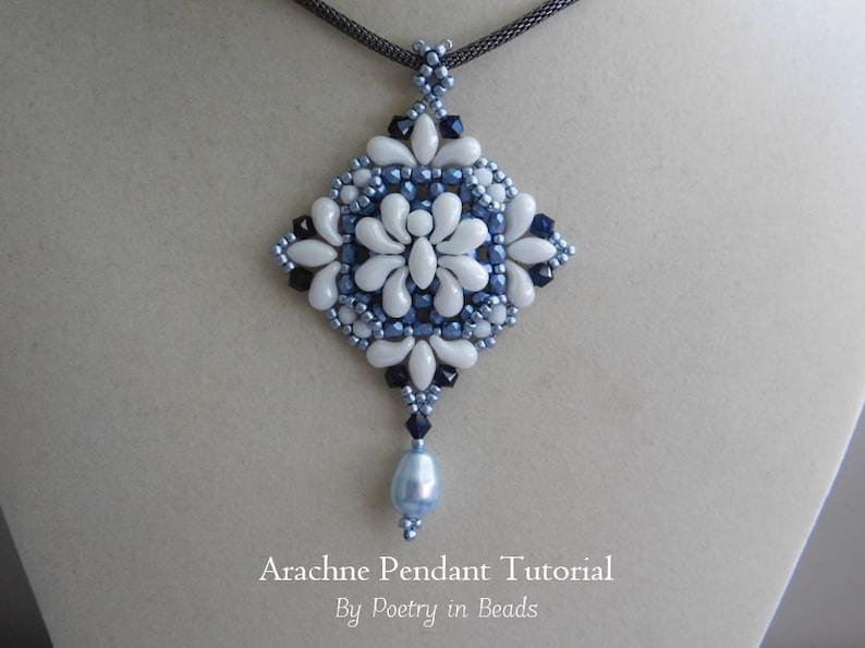 K&ouml;nnte beinhalten: Ein wei&szlig;er und blauer Perlenanh&auml;nger mit einer tropfenf&ouml;rmigen Perle, die an der Unterseite h&auml;ngt. Der Anh&auml;nger hat die Form eines Diamanten und ein florales Design. Der Text "Arachne Pendant Tutorial By Poetry in Beads" befindet sich unter dem Anh&auml;nger.