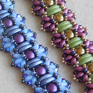 Puede incluir: Dos pulseras de cuentas con intrincados patrones. Una pulsera presenta cuentas azules, moradas y plateadas, mientras que la otra presenta cuentas verdes, moradas y doradas.