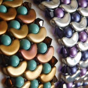 Könnte beinhalten: Nahaufnahme von zwei Armbändern mit Perlen. Ein Armband hat goldene, bronzefarbene und türkisfarbene Perlen. Das andere Armband hat silberne, violette und dunkelblaue Perlen. Beide Armbänder haben ein einzigartiges, strukturiertes Design mit einer Mischung aus runden und halbmondförmigen Perlen.