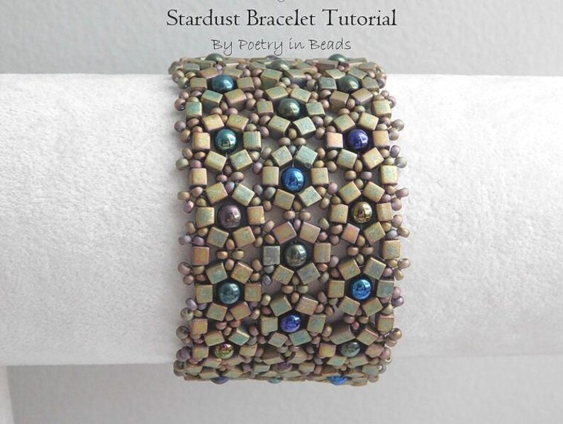 Pu&ograve; includere: Un braccialetto di perline con un motivo geometrico in tonalit&agrave; di marrone, blu e verde. Il braccialetto &egrave; realizzato con piccole perline quadrate e presenta un design a forma di stella che si ripete. Il titolo "Stardust Bracelet Tutorial" e "By Poetry in Beads" sono visibili sopra il braccialetto.