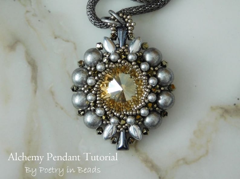 Pode incluir: Um pingente de contas prateadas e douradas com um grande cristal facetado de cor &acirc;mbar no centro. O pingente est&aacute; preso a uma corrente de prata.