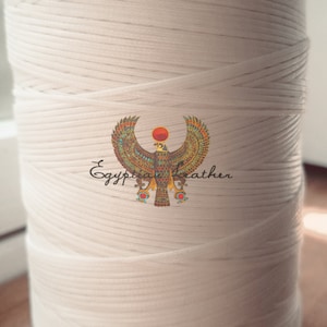 May include: A large spool of white macrame cord. The cord is tightly wound and has a textured appearance. The image includes a logo with an Egyptian-inspired design and the text "Egyptian Leather".