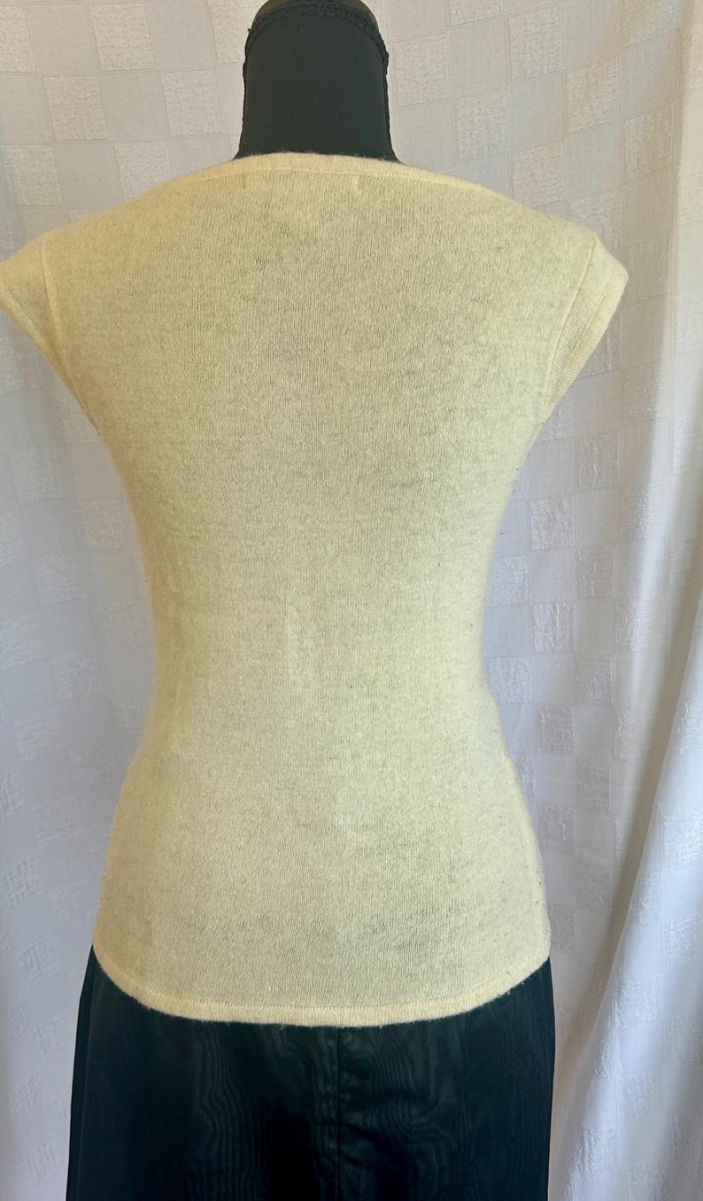 Puede incluir: Top de punto amarillo p&aacute;lido con cuello redondo y mangas cortas. El top ajustado se muestra en un maniqu&iacute;, mostrando su silueta ajustada. La tela parece suave y ligeramente texturizada, sugiriendo un uso c&oacute;modo.