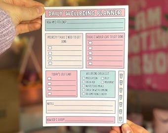 May include: A daily wellbeing planner with a pink and blue color scheme. The planner includes sections for how you are feeling, priority tasks, tasks you would like to get done, today's self care, wellbeing checklist, notes, and how did you sleep.