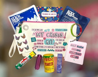May include: A collection of items for self-care, including a canvas pouch with the words "My Crisis Kit," a word search book, a bracelet, a cooling pack, and a variety of small treats and tools. The kit is designed to provide comfort and support.