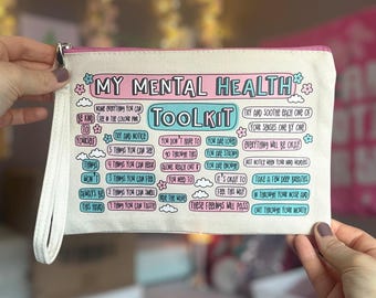 May include: A white canvas zippered pouch with a pink zipper pull. The pouch has a pink and blue design with the text "My Mental Health Toolkit" and a list of coping mechanisms.