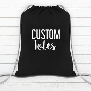 May include: Black drawstring bag with white text that reads "CUSTOM Totes".