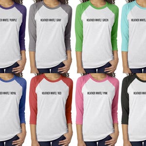 May include: A set of ten baseball t-shirts in various color combinations. The shirts are heather white with a contrasting color on the sleeves. The colors include purple, gray, green, light blue, royal blue, red, pink, and black.
