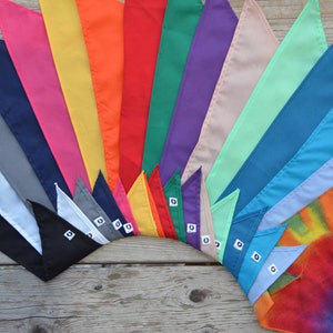 May include: A collection of 17 colorful fabric bandanas arranged in a fan shape. The bandanas are in various colors, including white, black, gray, pink, yellow, orange, red, green, purple, beige, light blue, dark blue, and light purple. The bandanas are all folded in a triangular shape and have a small white tag with a number on it.