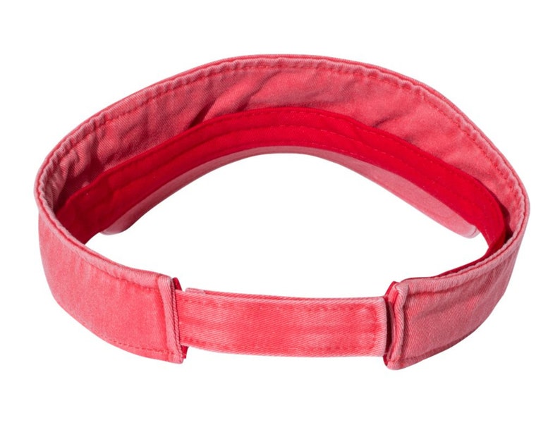 May include: A red visor made of cotton with a fabric strap. The visor is designed to protect the eyes from the sun.